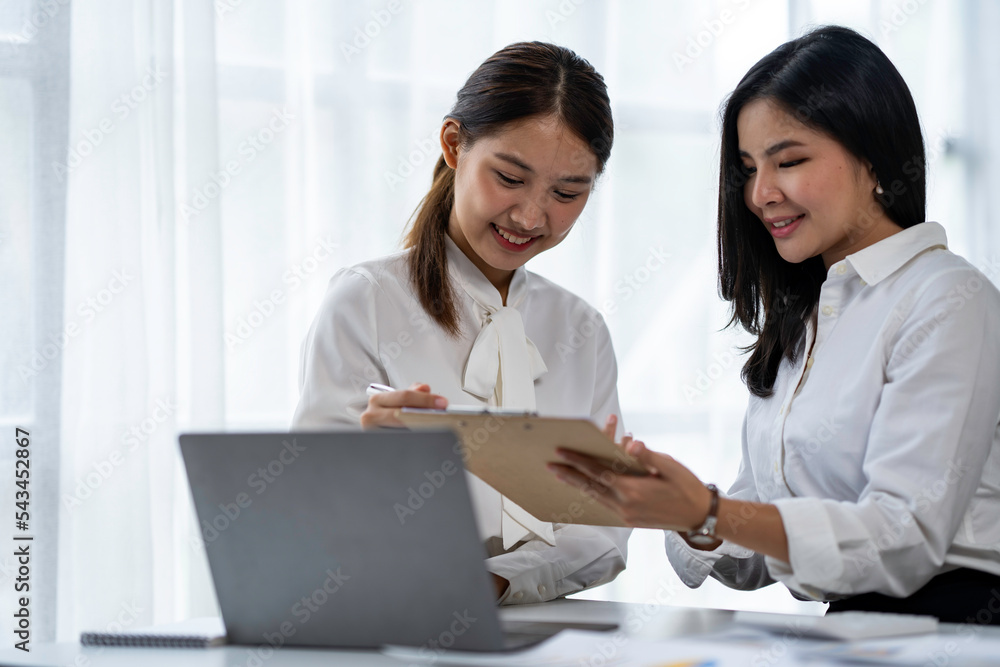 Two young Asian businesswomen talk, consult, discuss working with new startup project idea presentation analyze plan marketing and investment in the office. Two young Asian businesswomen talk, consult, discuss working with new startup project idea presentation analyze plan marketing and investment in the office.
