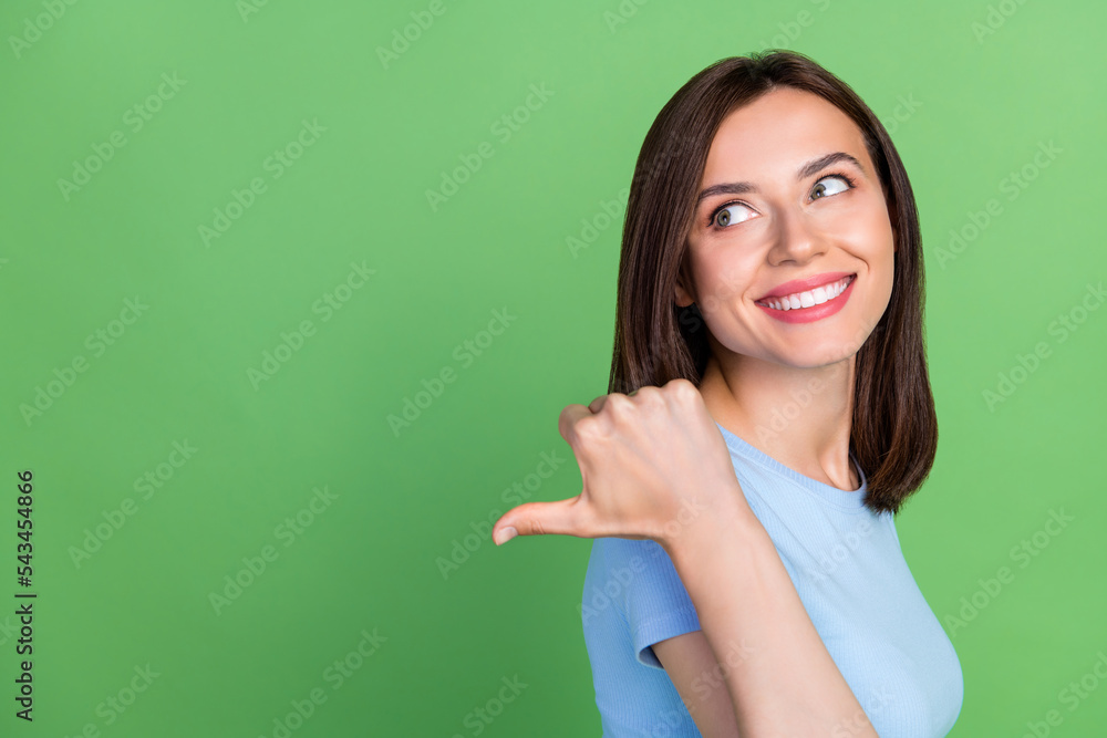 Profile photo of pretty positive person look indicate thumb finger empty space isolated on green color background Profile photo of pretty positive person look indicate thumb finger empty space isolated on green color background