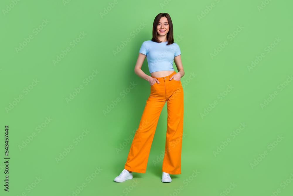 Full length photo of young attractive successful lady hands pocket promo new clothes collection isolated on green color background Full length photo of young attractive successful lady hands pocket promo new clothes collection isolated on green color background