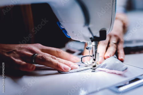Seamstress dressmaker working with sewing machine in workshop