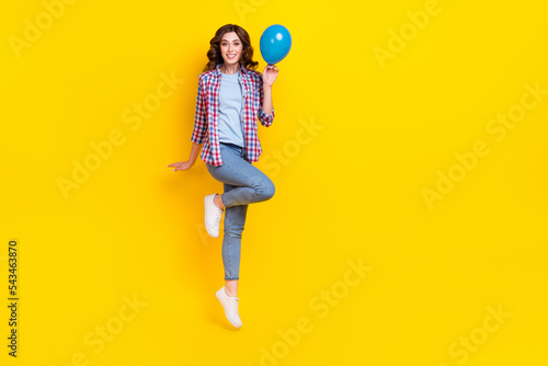 Full length photo of nice adorable gorgeous girl wavy hairdo checkered shirt hold blue balloon flying isolated on yellow color background © deagreez