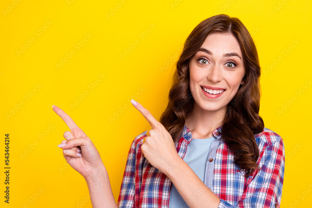 Photo of excited pretty young girl dressed checkered shirt pointing two fingers empty space isolated yellow color background Photo of excited pretty young girl dressed checkered shirt pointing two fingers empty space isolated yellow color background
