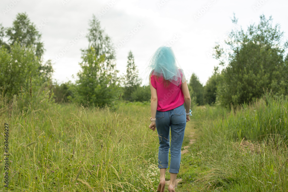 Girl stands on path in park. Nature walk. Bridesmaid went into woods.