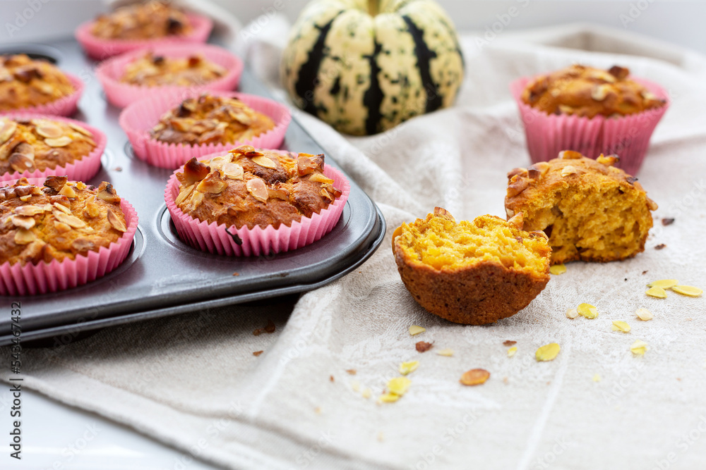 Homemade pumpkin muffins with pumpkin seeds and walnut pieces. Fall baking for Thanksgiving and Halloween. Cupcakes in baking dish on linen napkin. Selective focus. Close up. Homemade pumpkin muffins with pumpkin seeds and walnut pieces. Fall baking for Thanksgiving and Halloween. Cupcakes in baking dish on linen napkin. Selective focus. Close up.
