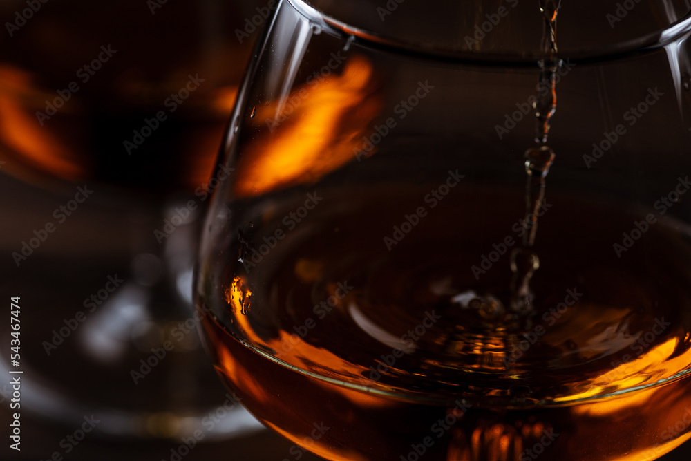 Two glasses of cognac are on a wooden table Two glasses of cognac are on a wooden table