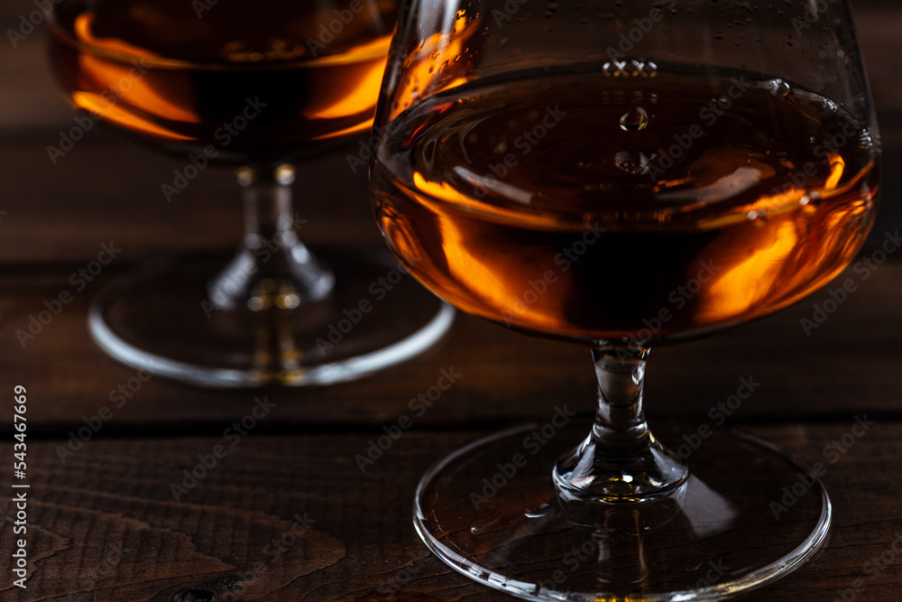 Two glasses of cognac are on a wooden table