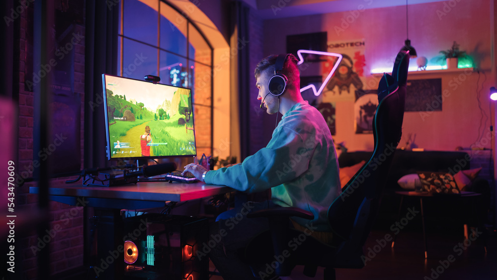 Successful Gamer Playing and Winning in PvP Shooter Video Game in Which Players Fight in a Battle Royale Tournament on Personal Computer. Stylish Man Celebrating Victory in Cozy Room at Home.