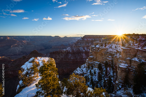 Winter sunrise at Grand Canyon Arizona with snow on the cliffs and the sun peaking above the canyon rim