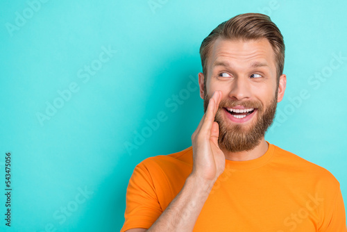 Photo of impressed brown hairdo guy look promo wear orange t-shirt isolated on turquoise color backgroiund photo