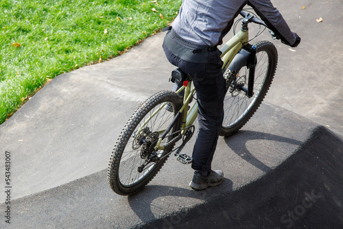 A man is sitting on a bicycle, rear view. The cyclist is preparing to start on the pump track. Extreme sports.