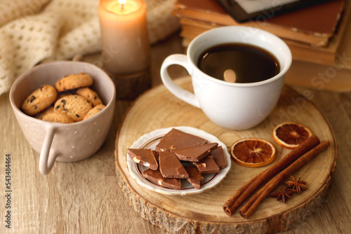 Bowl of cookies, cup of tea or coffee, chocolate, spices, knitted blanket, books, glasses and candle on the table. Cozy hygge atmosphere at home. Selective focus. © jelena990