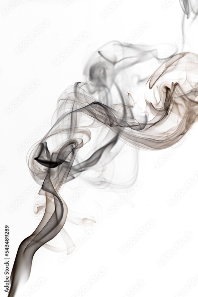 Puffs and curls of dark smoke on a white background rising from a burning stick