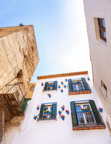 Facade of a traditional andalucian house with a ancient tower in the touristic village of Torremolinos, Malaga in Spain. White building with flowers in the balconies. photo
