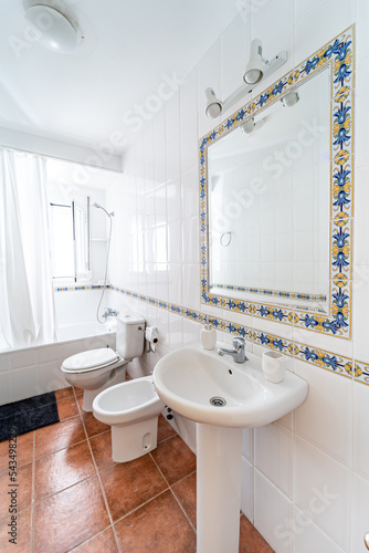 Clean bright bathroom interior with white toilet and traditional tiles. Original designed hotel space with bathtub