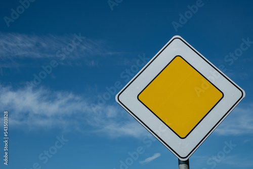 Road sign "Main road" against the blue sky. A symbol of priority over other road users. Summer. Day.