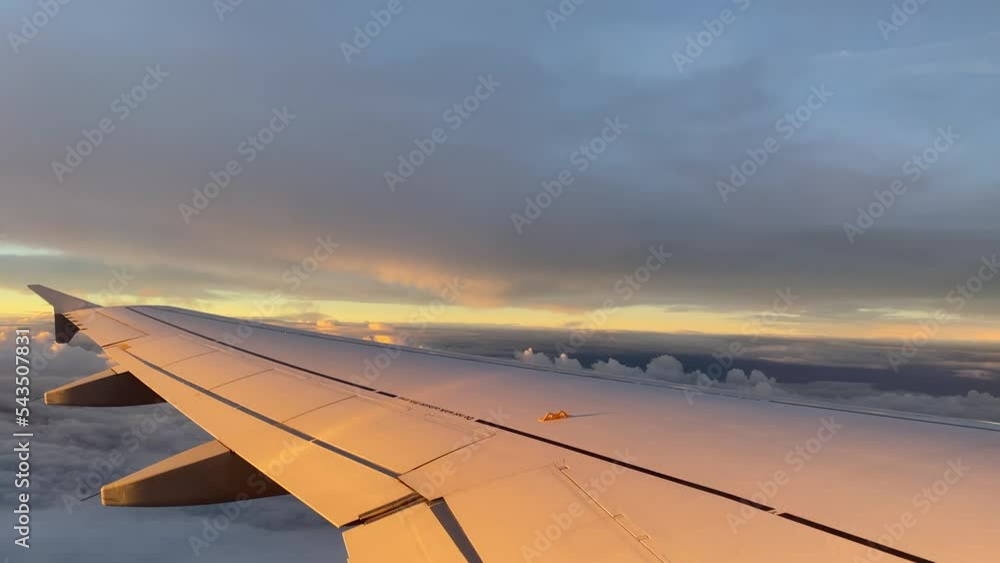 Airplane wing during sunset with dramatic sky in the background. Dramatic clouds during sunset. Airplane wing against the dark sky background. Aviation scene during landing. In-flight view on wing. Airplane wing during sunset with dramatic sky in the background. Dramatic clouds during sunset. Airplane wing against the dark sky background. Aviation scene during landing. In-flight view on wing.