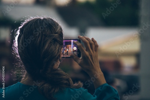 Stampa su tela Woman shoots an event on smartphone, rear view