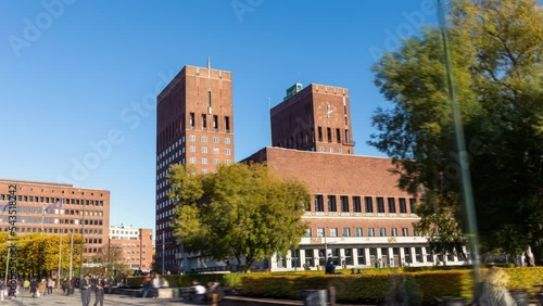 Oslo city hall (radhus, radhuset) hyper-lapse: time-lapse of the capital of Norway, featuring red brick building and two towers, on a sunny day, under clear blue sky, with people walking on the square