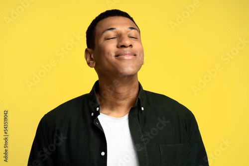 Portrait of handsome man posing with positive facial expression, closed eyes with smile
