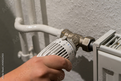 A hand turns the thermostat on a heater