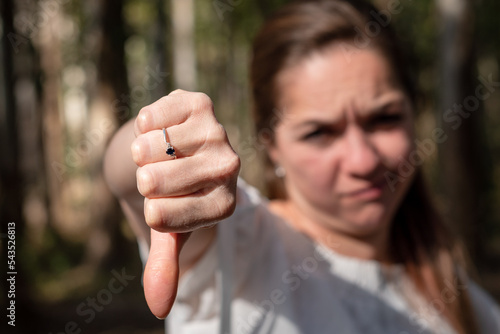 Mujer rechazando con el gesto de pulgar abajo, mostrando su puño a cámara. Fotografía con enfoque selectivo en la mano photo