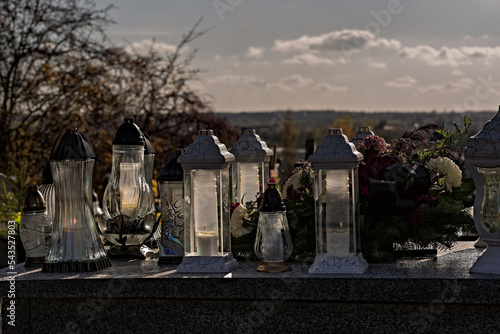 Dzień Wszystkich Świętych . Dzień zaduszny ( Zaduszki) . Grobowiec na cmentarzu parafialnym ustrojony kwiatami i wieńcami i płonącymi zniczami . 