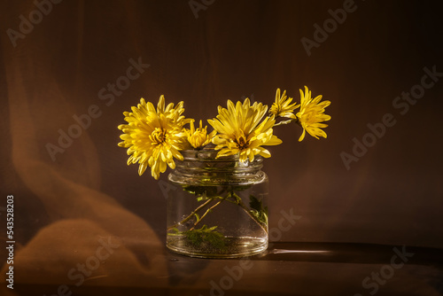 Still life with a bouquet of yellow flowers in a glass can 