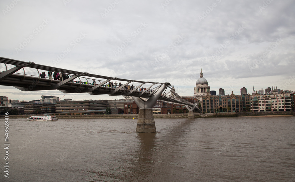 Fototapeta premium The Millenium Bridge and the enormous dome of Saint Paul Cathedral and a clock tower, London, England.