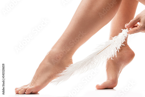 Female feet with smooth skin and soft ostrich feather on white background photo