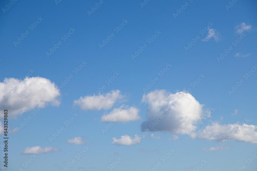 Obraz premium Bright blue sky with many beautiful white clouds for background or wallpaper. The beauty of nature for graphic design, natural beauty, ecology and clean air. Natural textures.