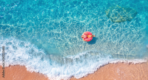 Concept banner tropical paradise travel relax. Aerial top view young woman swimming with donut pink inflatable swim ring in blue sea
