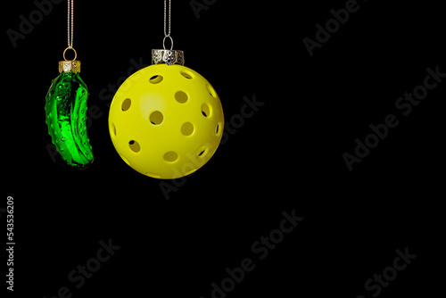 Christmas Pickleball.  Christmas Pickle with yellow Pickleball decoration on a black background.  lots of room for text.