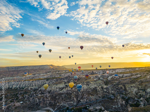 Spectacular drone view of hot air balloons ride over Turkey's iconic Cappadocia, the underground cities and fairy chimneys valley, rock formations, in the sunlight. High quality photo