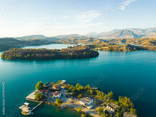 Green lake Manavgat surrounded by mountain landscape and cliffs, with little islands, buildings, and roads. Sunny weather, blue sky. High quality photo