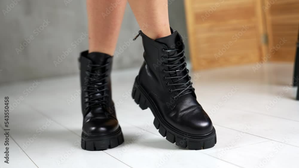 Female wearing the black low autumn boots with laces. Model turning in front of camera showing stylish footwear. Close up. White backdrop. Female wearing the black low autumn boots with laces. Model turning in front of camera showing stylish footwear. Close up. White backdrop.