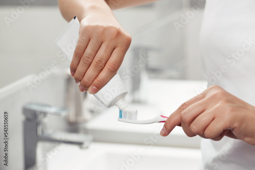 Woman applying toothpaste on brush in bathroom, closeup © New Africa