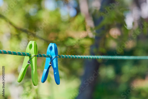 Two colored clothespins hang from the rope where the laundry dries outdoors.