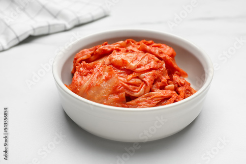 Bowl of spicy cabbage kimchi on white marble table