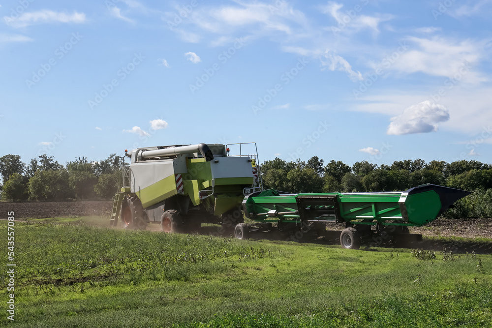 Fototapeta premium Modern combine harvester with header near agricultural filed