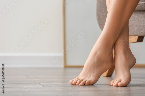 Barefoot legs of woman sitting in armchair at home