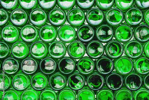 Glass bottles green. Green glass bottles of beer. Wall formed by green bottles. Green bottles background. Empty Glass Bottle with Lighting