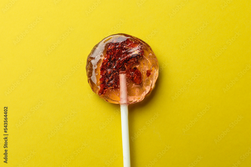 Sweet colorful lollipop with berries on yellow background, top view Sweet colorful lollipop with berries on yellow background, top view