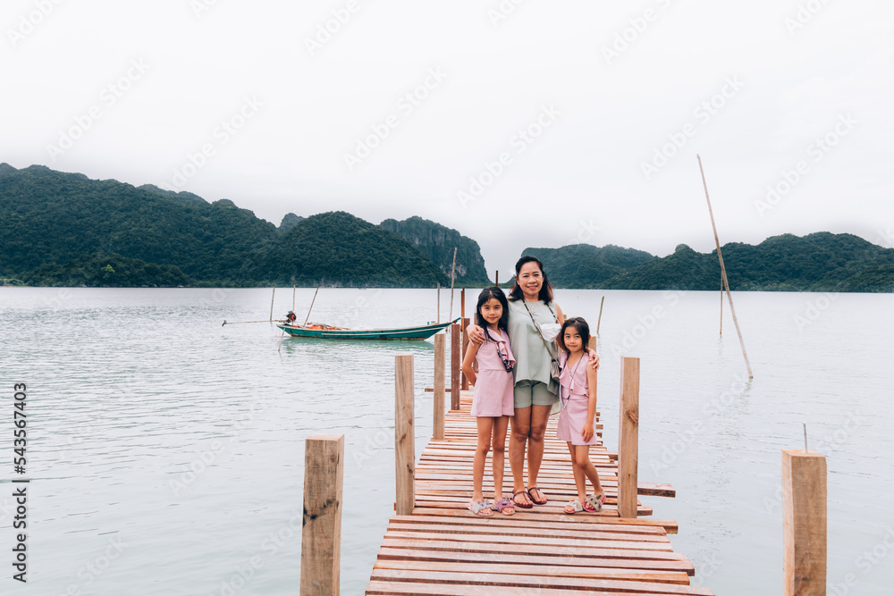 Naklejka premium My Traveler family on wooden bridge in the sea and mountain at Nakhon si thammarat Thailand