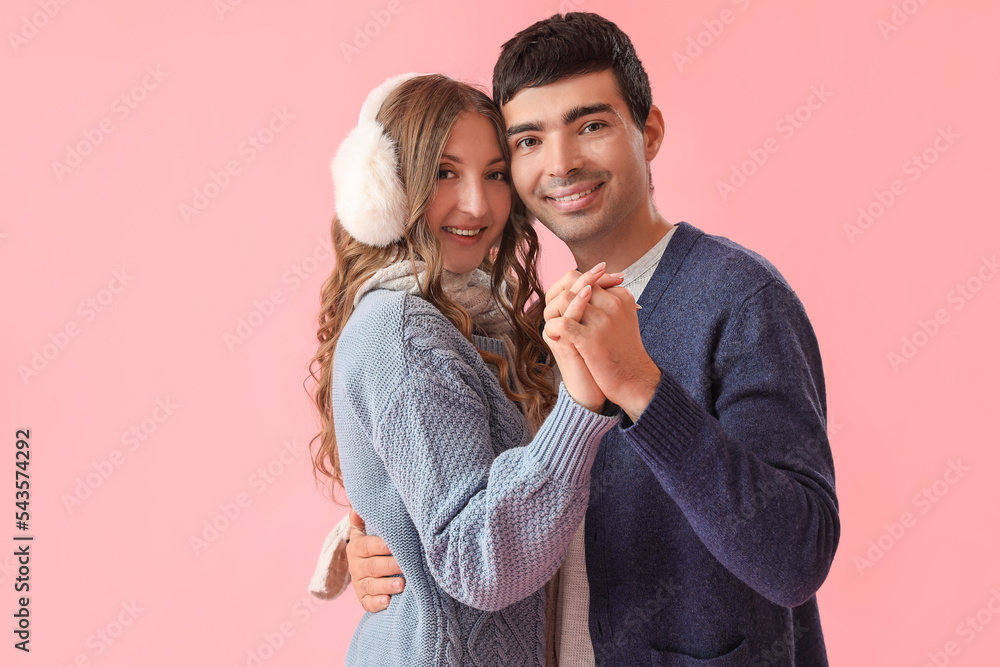 Loving couple in warm clothes holding hands on pink background Loving couple in warm clothes holding hands on pink background