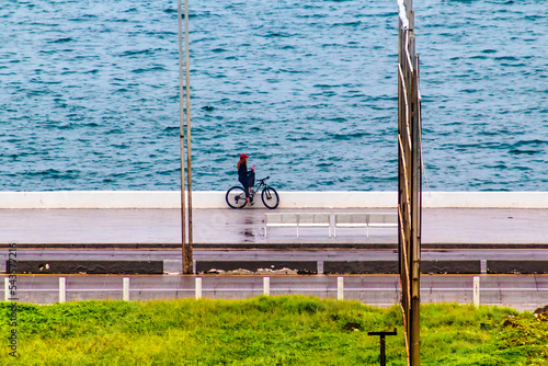 young woman riding a bike on the road in front of the beach, rainny day in boca del rio veracruz  photo