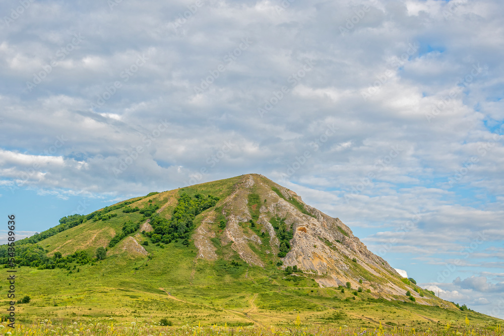 Green valley with pasture, relic mountain Shihan, blue cloudy sky in sun. Summer landscape. Green valley with pasture, relic mountain Shihan, blue cloudy sky in sun. Summer landscape.