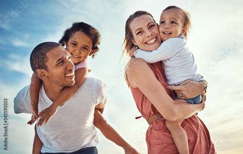 Happy family, blue sky and ocean, piggy back and hug for couple with kids on summer holiday at beach. Love, family and fun, man and woman smile with children sea for vacation time together at sunset. #543593033