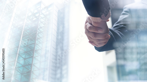 Photos Businessmen making handshake with modern buildings as background, business etiqu