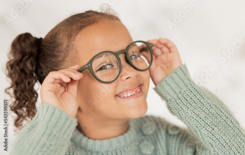 Face portrait, child and girl with glasses for optical health at optometrist office. Eyes wellness, eye care and happy kid with specs, spectacles or prescription lenses to help with ocular vision.