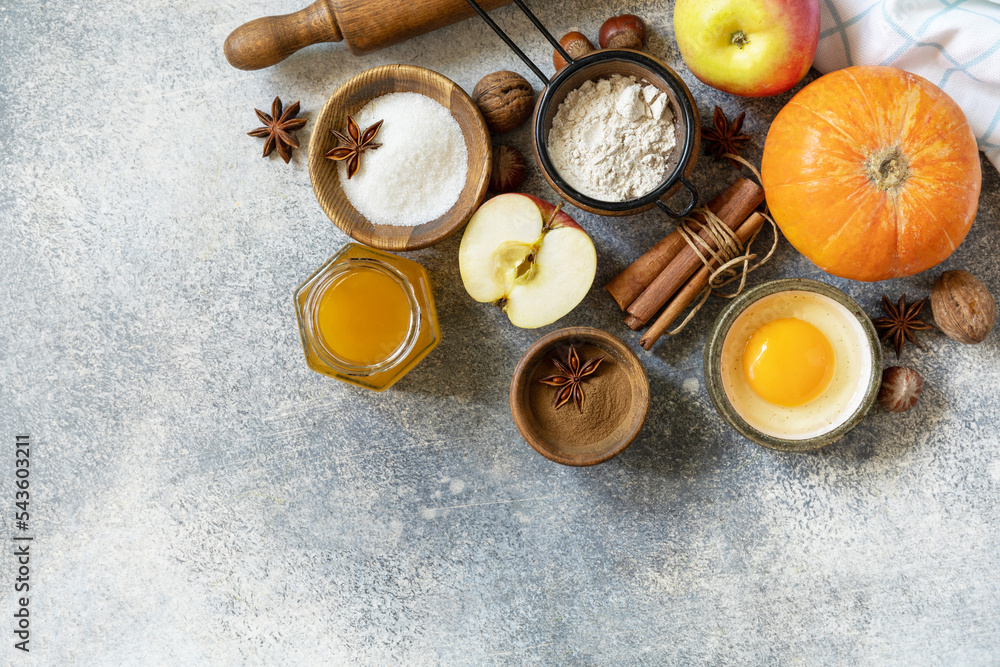 Baking food background. Pumpkins, apples, honey, nuts and seasonal spices for pumpkin or apple pie on a gray tabletop. View from above. Copy space. Baking food background. Pumpkins, apples, honey, nuts and seasonal spices for pumpkin or apple pie on a gray tabletop. View from above. Copy space.